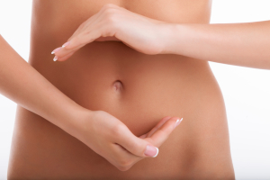 Close up of waist of healthy naked woman presenting dieting. She is holding her hands in circle shape in front of her stomach that symbolizes balance. Isolated on white background